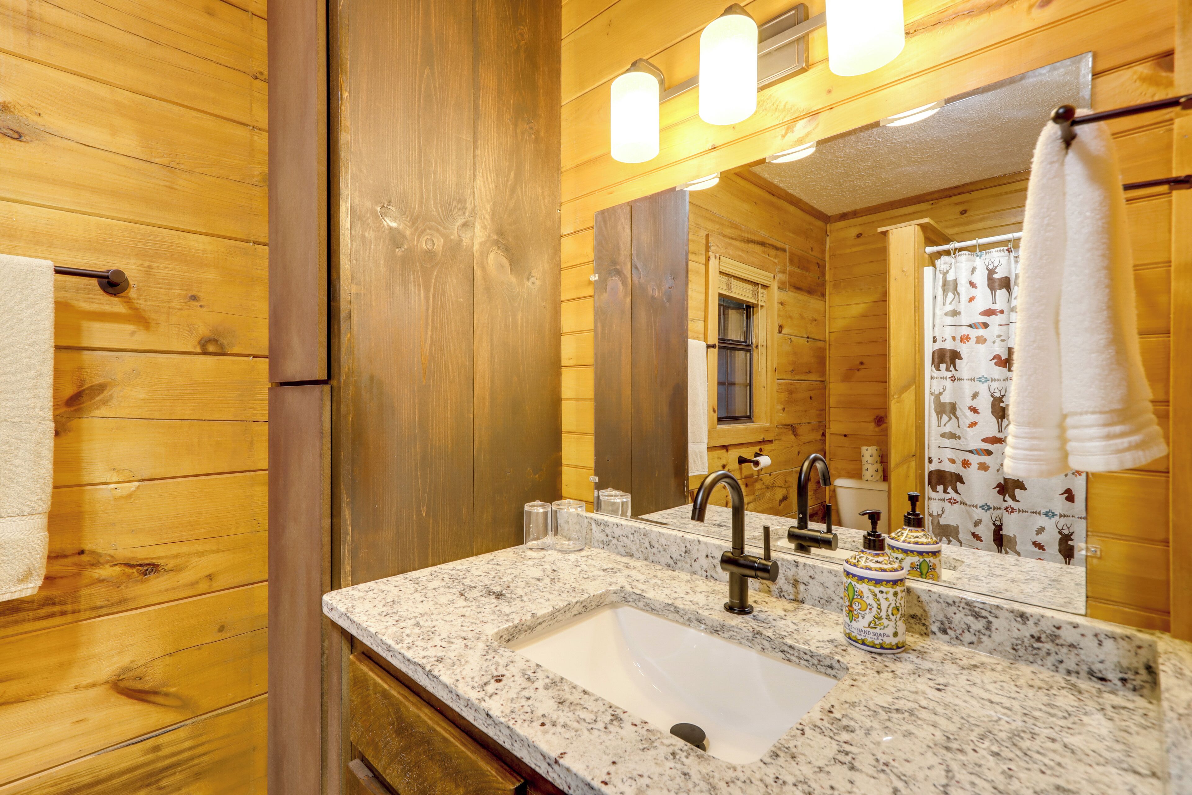 A wooden cabin bathroom with a granite sink, a mirror, and a towel hanging on the wall.