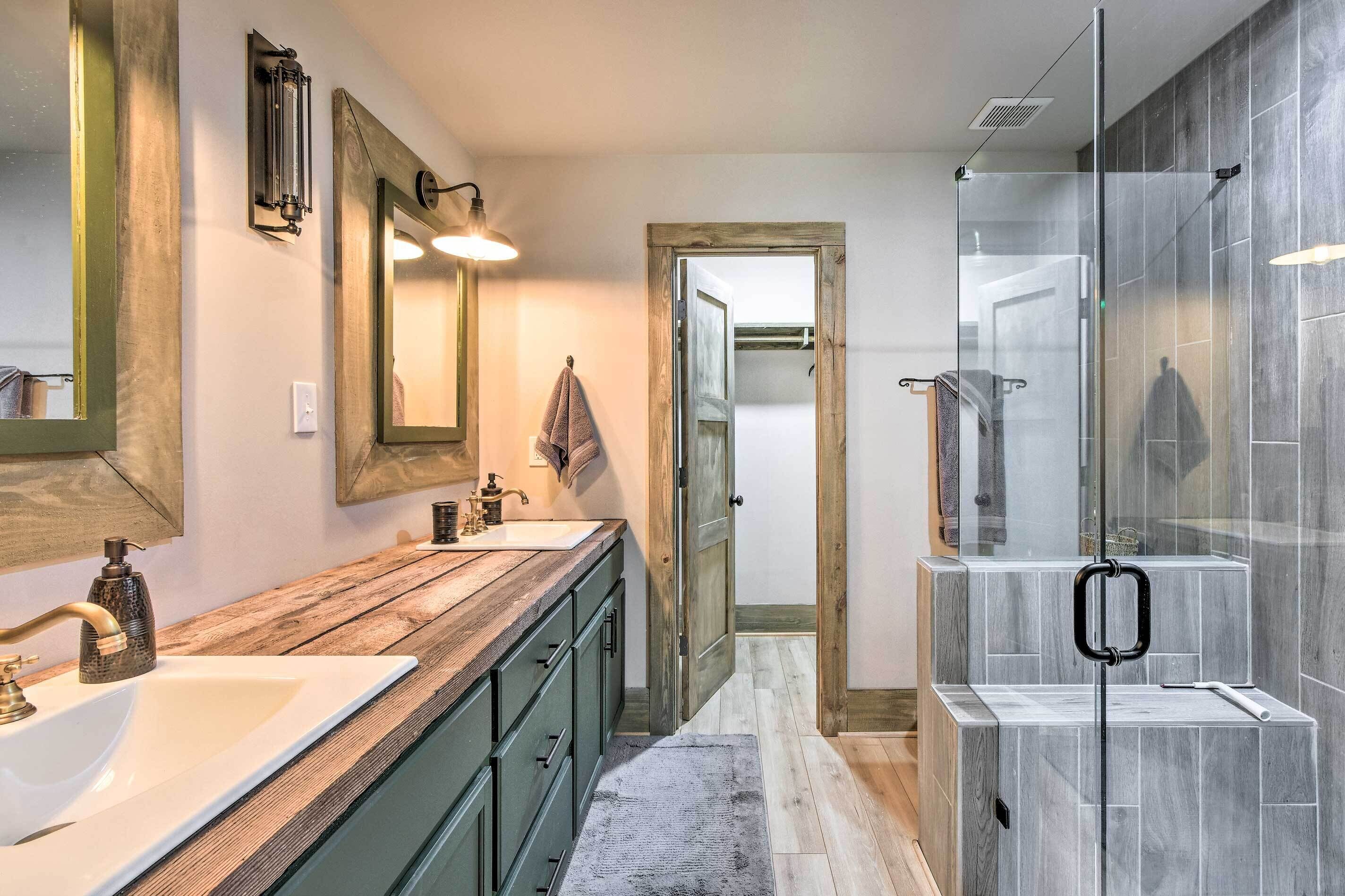 A bathroom with a wooden vanity, a large mirror, and a glass shower enclosure.