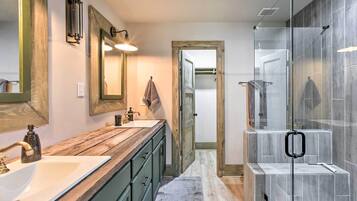 A bathroom with a wooden vanity, a large mirror, and a glass shower enclosure.