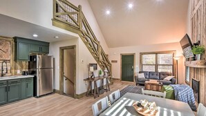 Un vaste espace de vie aménagé dans un style industriel, comprenant une cuisine, une table à manger, un escalier et un coin salon confortable.