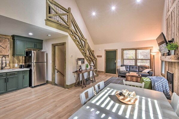Ein geräumiger Wohnbereich im Loft-Stil mit Küche, Esstisch, Treppe und einer gemütlichen Sitzecke.