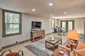 A spacious living room with a large TV, wooden furniture, and a dining area.