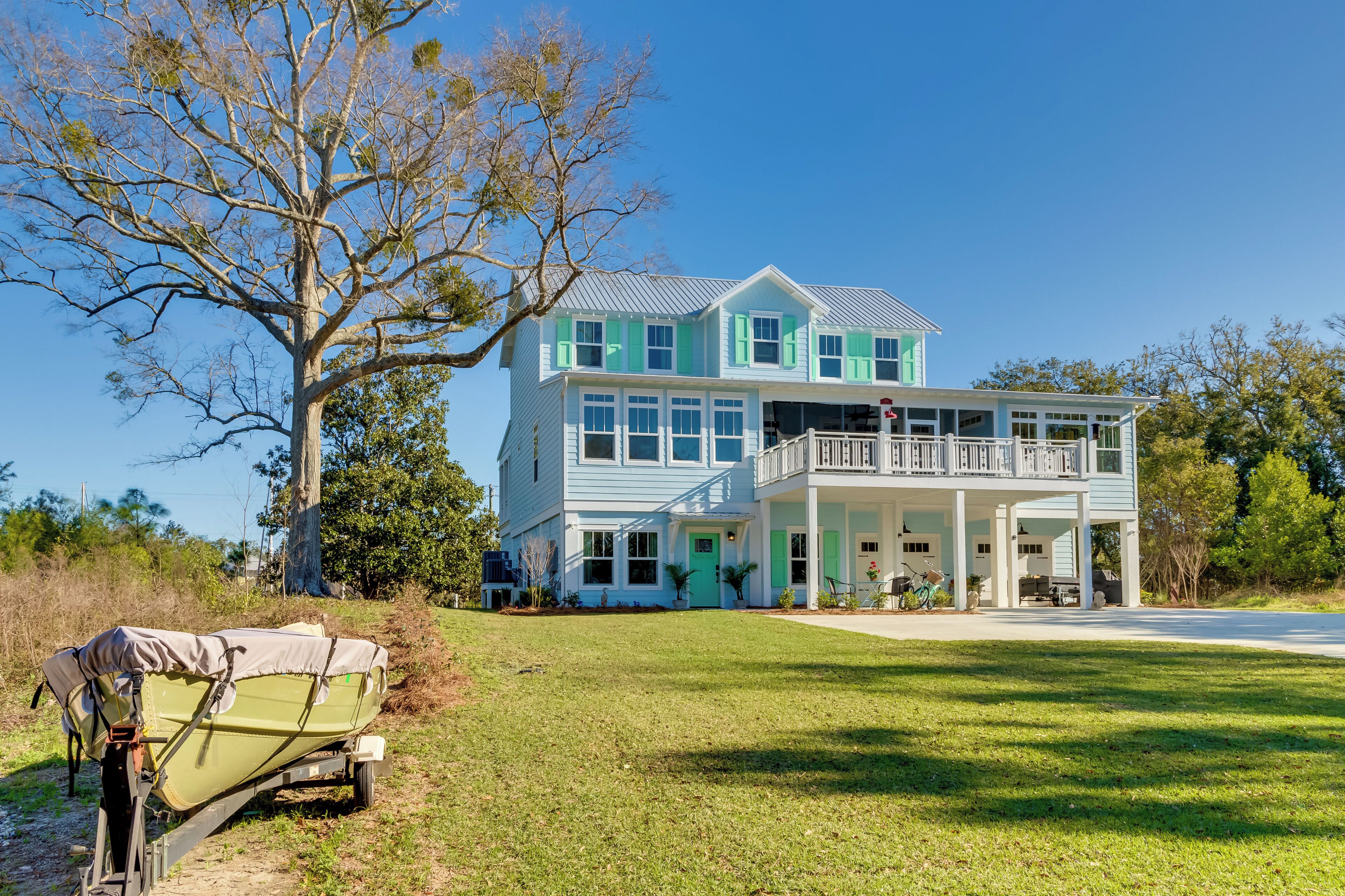A two-story house with a balcony, a covered boat, and a grassy yard.