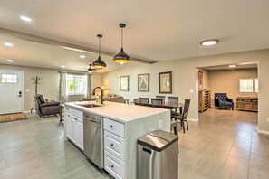 Una cocina amplia con una isla grande, iluminación colgante y un comedor con mesa y sillas.