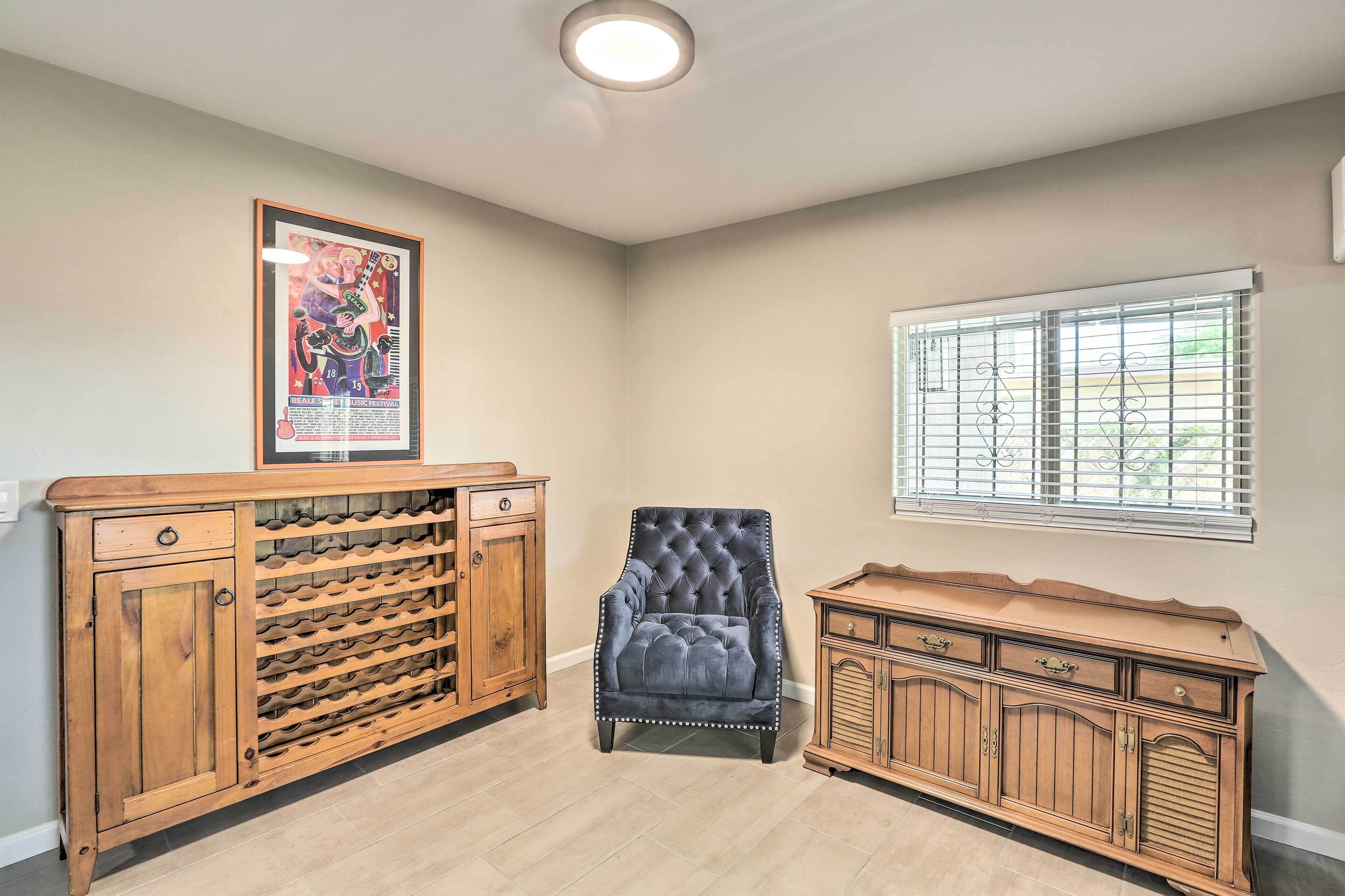 Una habitación con una estantería de madera para vino, un sillón capitoné y un mueble de madera.
