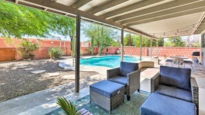 A covered patio area with outdoor furniture, a swimming pool, and a brick wall in the background. - Tucson Getaway w/ Private Pool & Gas Grill! (Tucson)