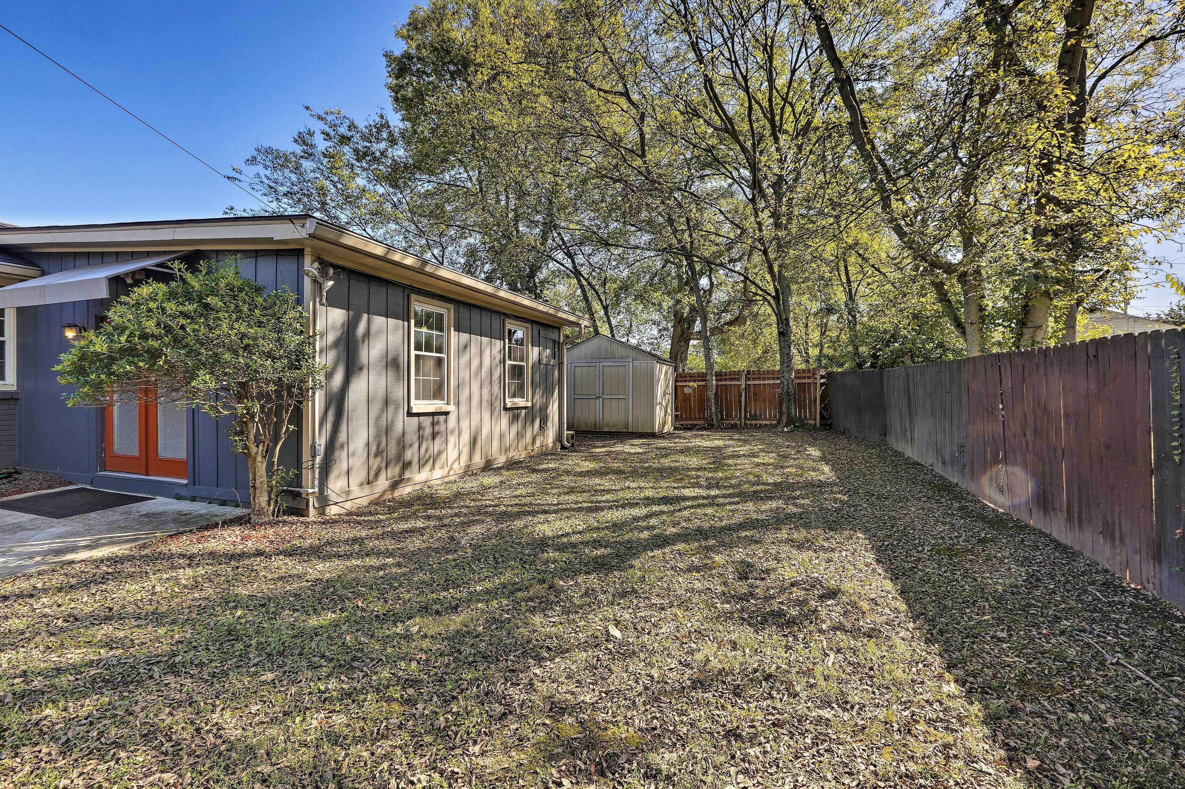 A residential backyard with a house, a shed, and a wooden fence.