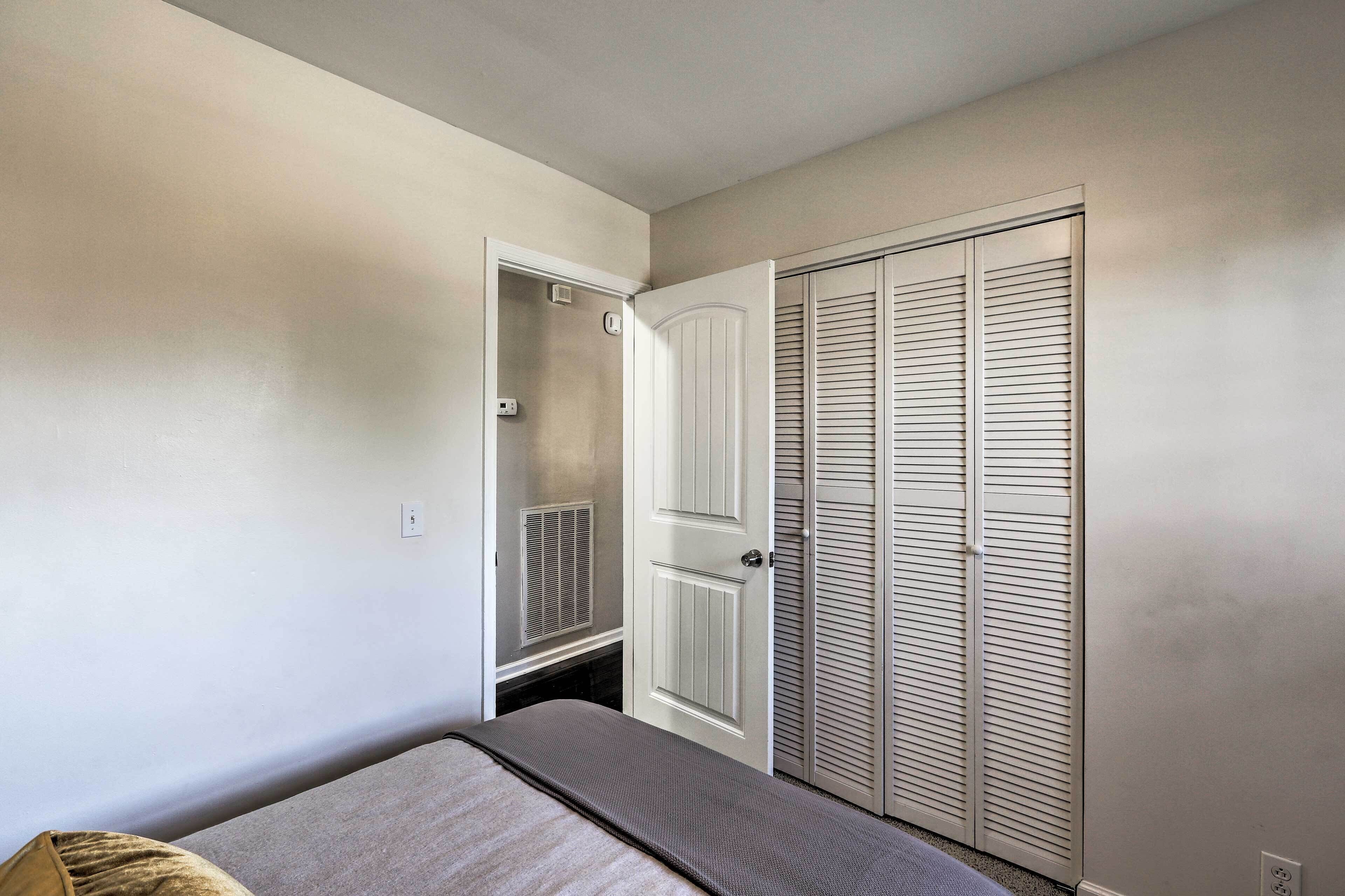 A bedroom with a bed, a closet with louvered doors, and a small window.