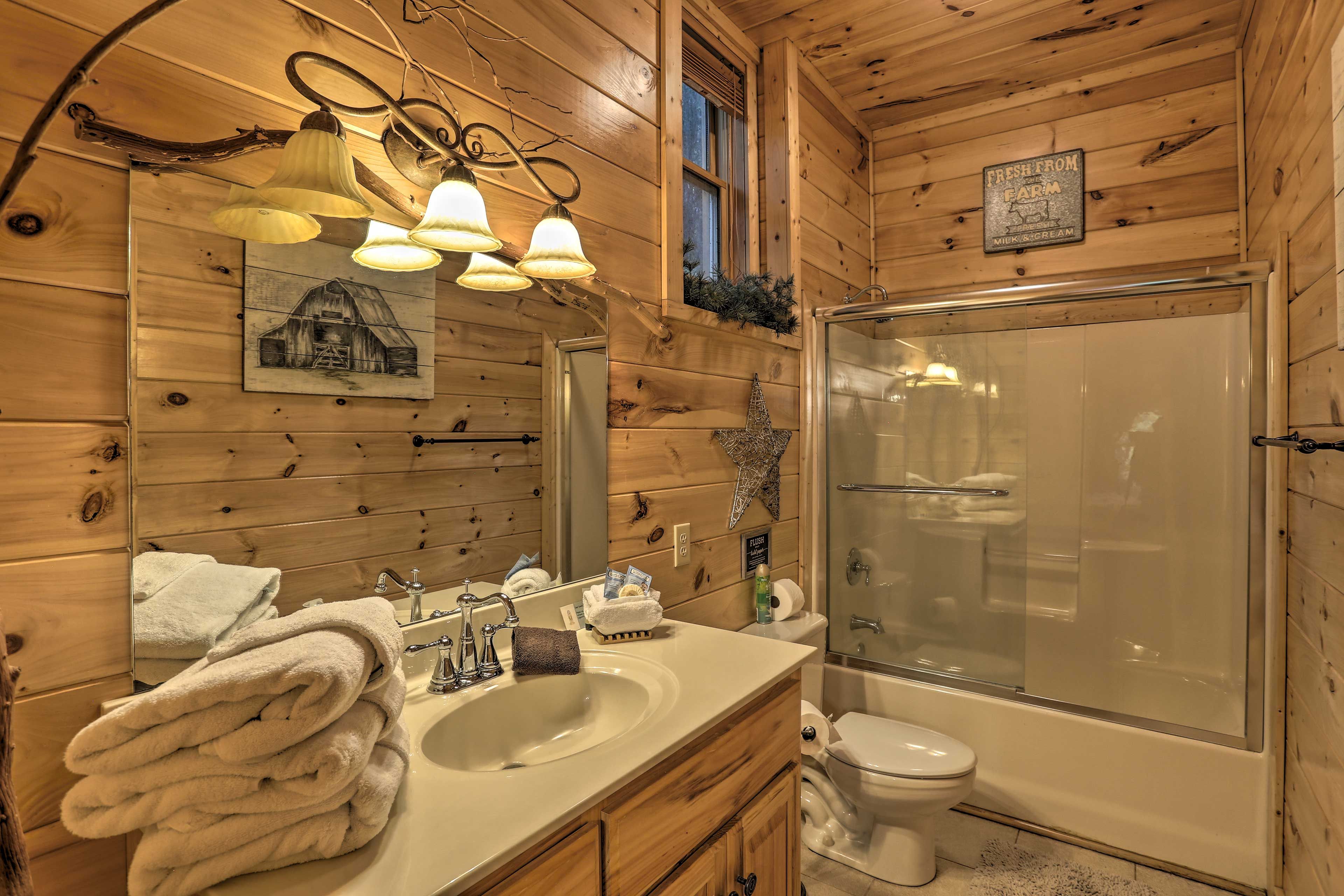 A wooden cabin bathroom with a sink, mirror, and a glass-enclosed shower.