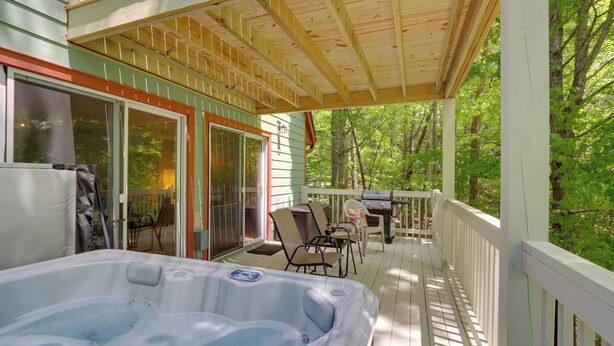 A wooden deck with a hot tub, outdoor furniture, and a view of the forest. - Blue Ridge Getaway w/ Hot Tub & Seasonal View! (Blue Ridge)