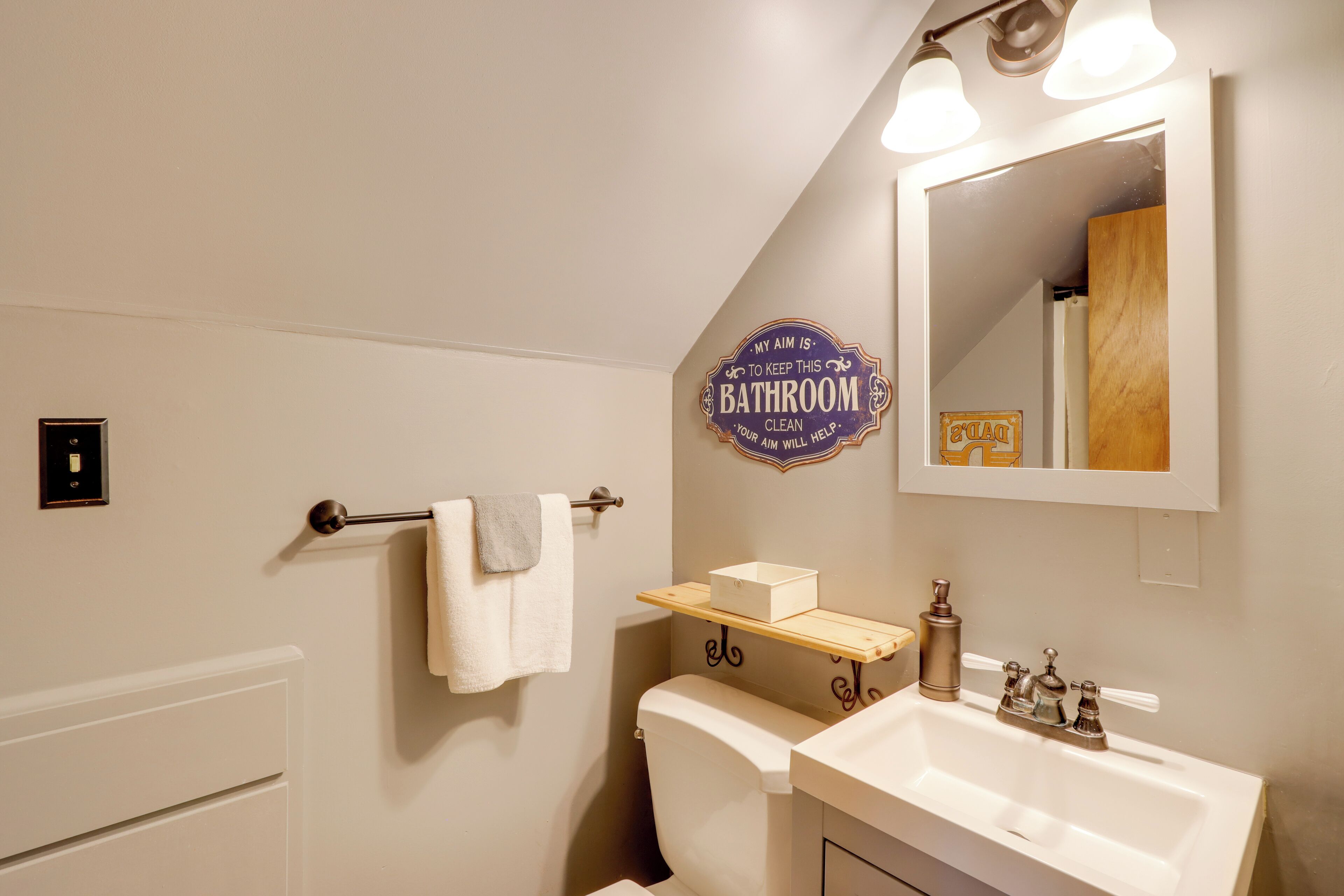 Une salle de bain équipée de toilettes, d’un lavabo, d’un miroir et d’un porte-serviettes.