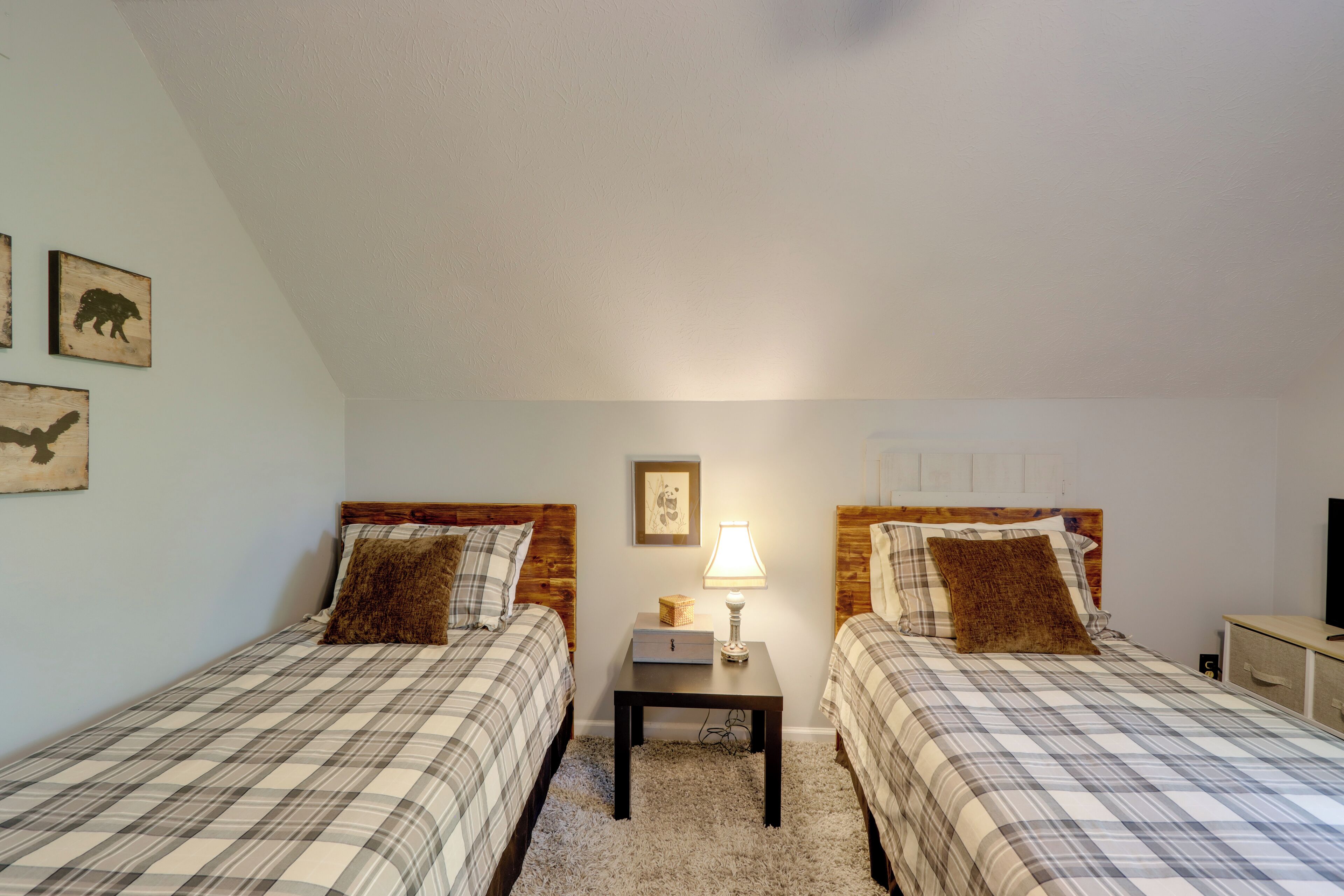 A bedroom with two beds, a nightstand with a lamp, and a television on a dresser.