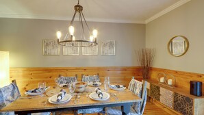 A dining area with a wooden table set for four, surrounded by chairs, a chandelier, and artwork on the walls. - Blue Ridge Getaway w/ Hot Tub & Seasonal View! (Blue Ridge)