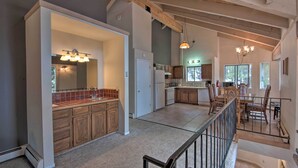 A spacious kitchen with wooden cabinets, a large island, and a dining area with a high ceiling and exposed beams. - Stateline Ski House: Walk to Boulder Lift! (Stateline)