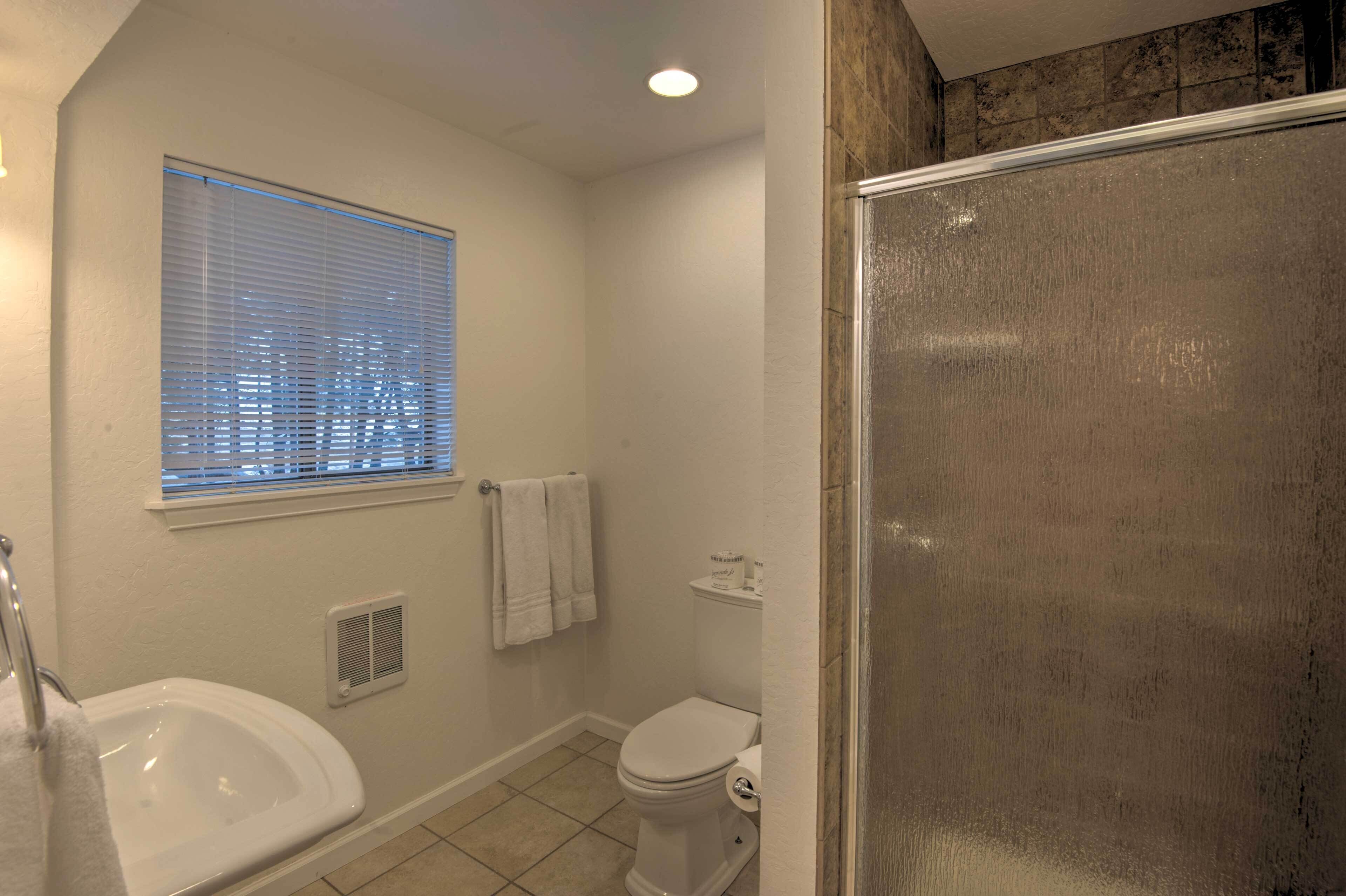 A bathroom with a toilet, sink, and window with blinds.
