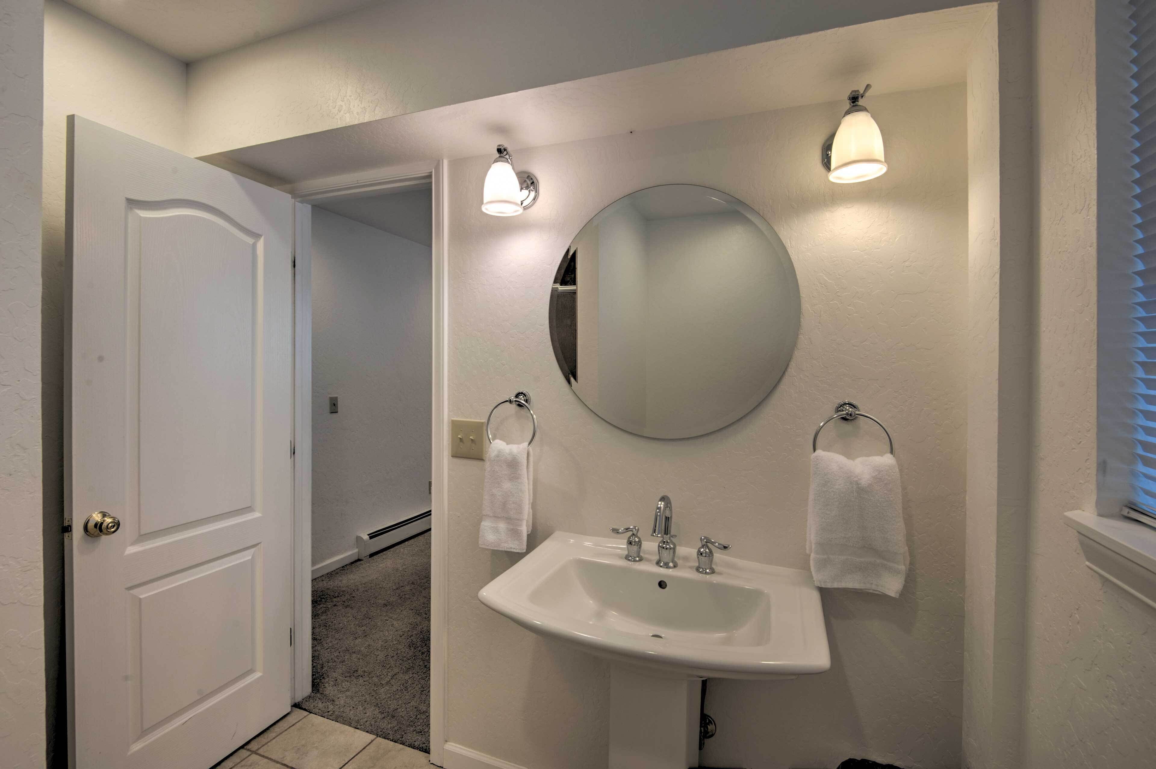 A bathroom with a white sink, a round mirror, and two wall-mounted lights.