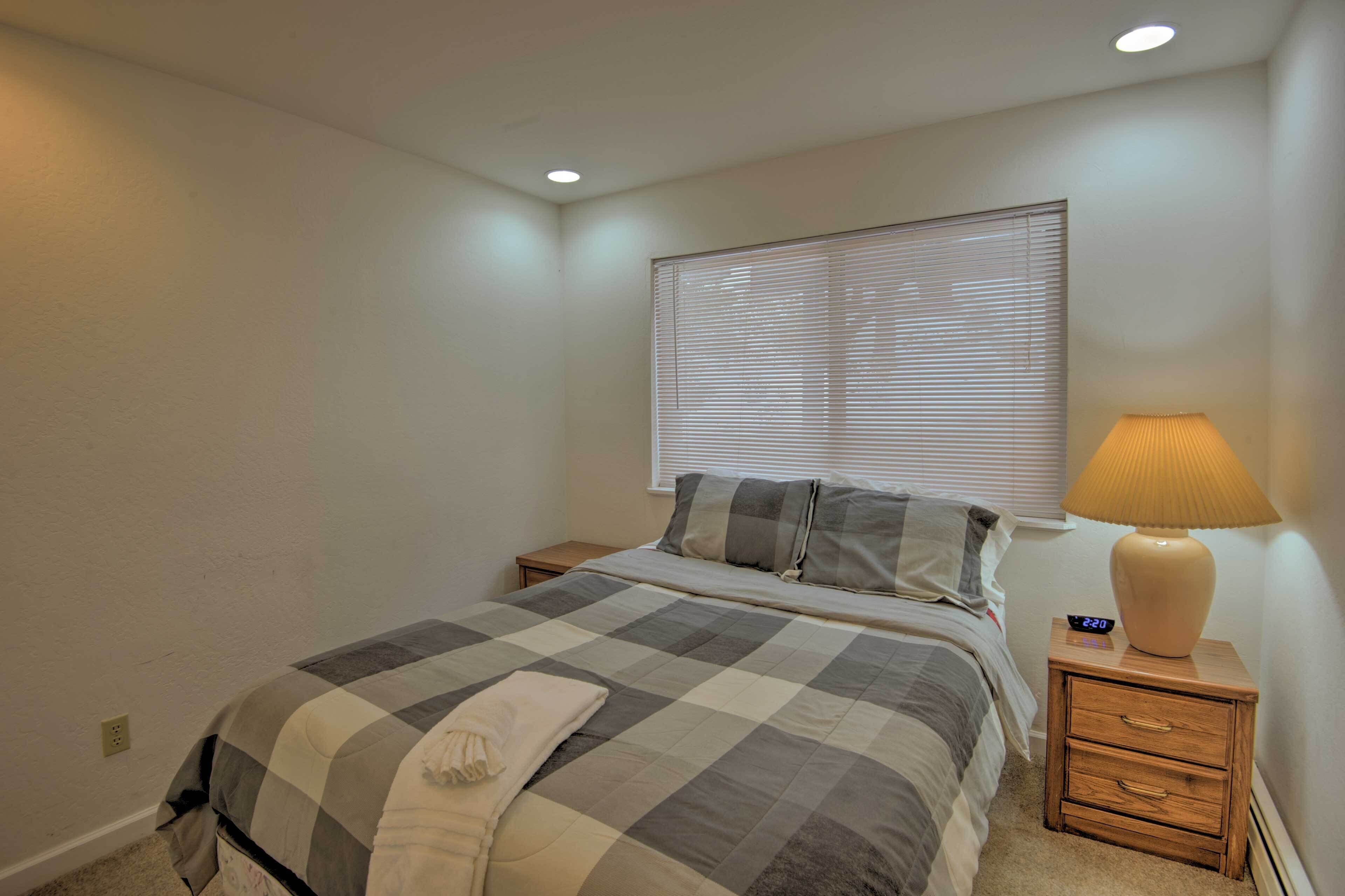 Un dormitorio con cama, mesita de noche, lámpara y reloj digital.
