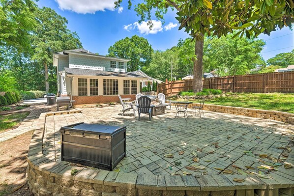 A backyard with a patio, outdoor furniture, and a large windowed structure.