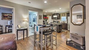 A modern kitchen with a central island, a dining area with bar stools, and a living room with a brown leather chair. - Nashville Home w/ Fire Pit & Yard, 3 Mi to Dwtn (Nashville)
