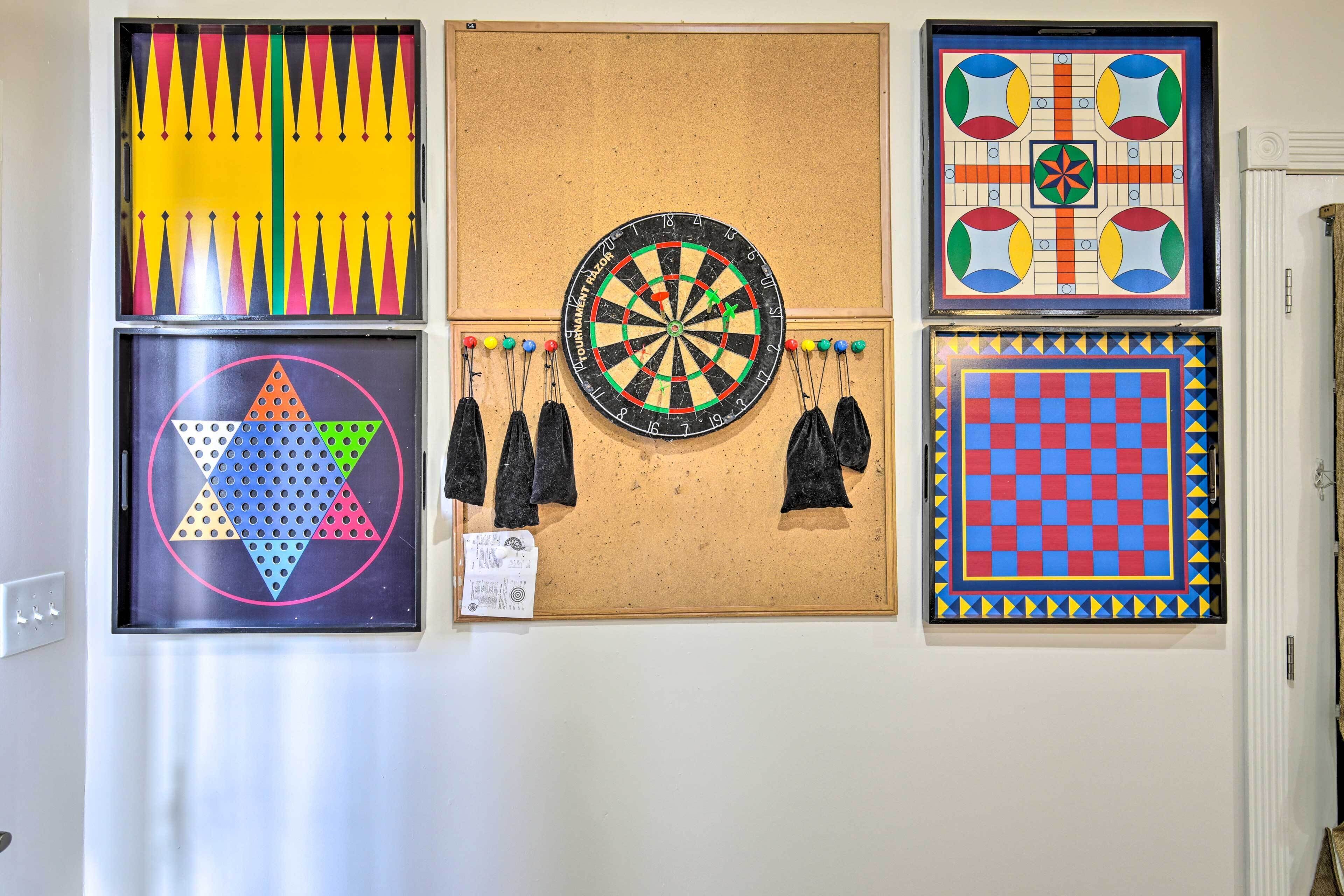 A wall with various framed artworks, including a dartboard and geometric patterns.