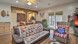 A living room with a brown leather sofa, a wicker armchair, and a quilted throw. - Cozy & Quiet Studio w/ Porch, Near Scenic Railway! (Blue Ridge)