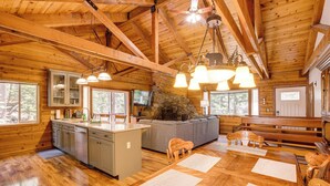 A spacious cabin interior with a wooden interior, a stone fireplace, a large sofa, and a dining area with wooden chairs. - 4 Mi to Beach: Lake Tahoe Mountain Retreat! (Stateline)