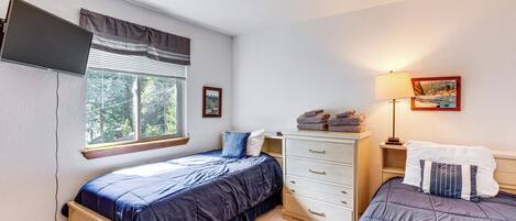 A bedroom with two beds, a dresser, a window with blinds, a lamp, and a painting on the wall.