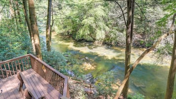 Terraza de madera con vista a un río en zona boscosa.