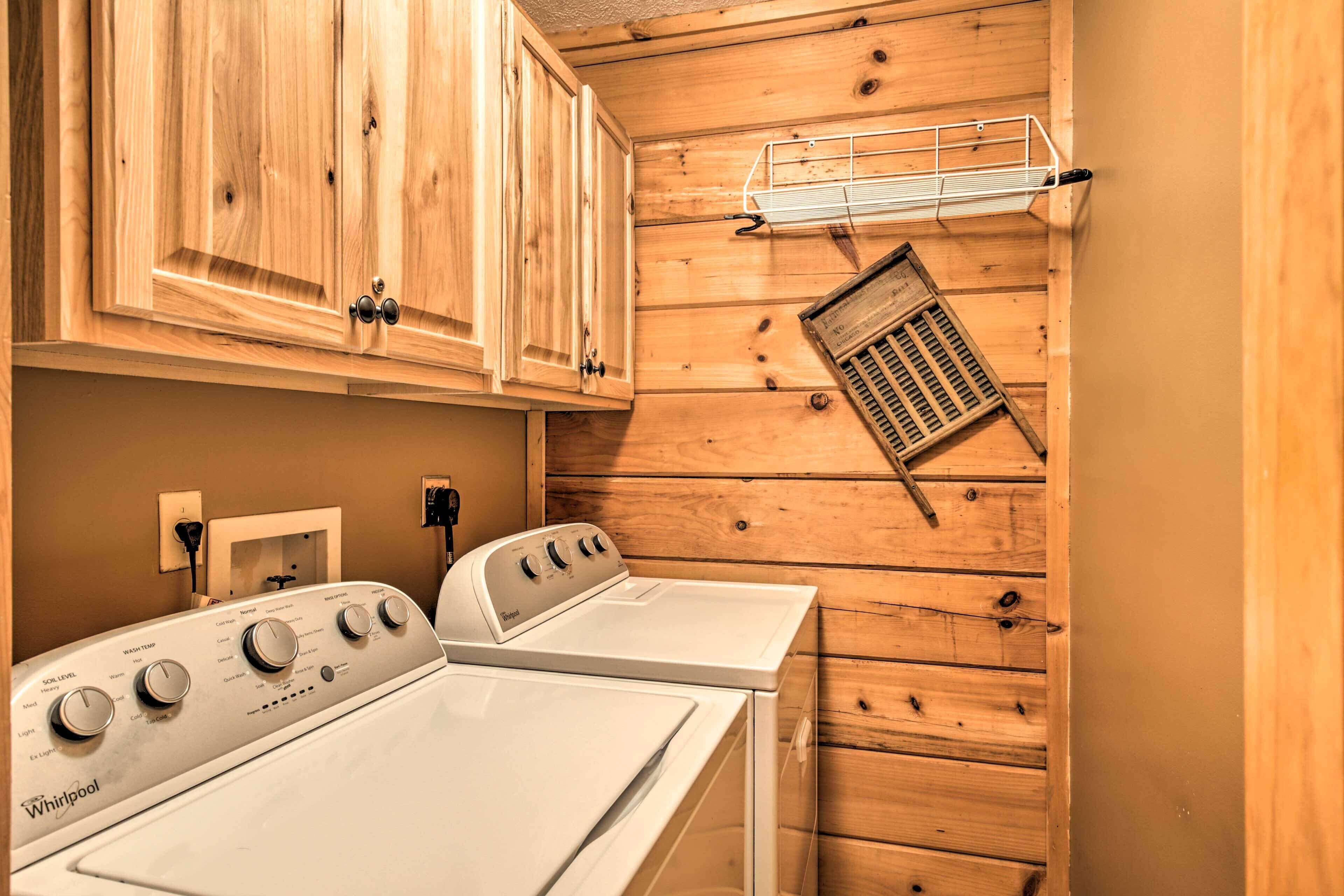 Un cuarto de lavado con paredes de madera, una lavadora Whirlpool blanca y un tendedero de metal.