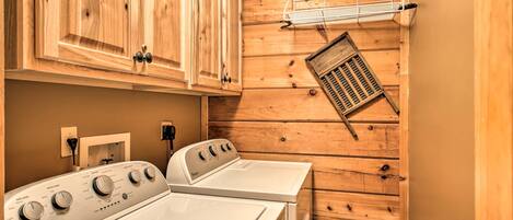 A laundry room with wooden walls, a white Whirlpool washer, and a metal drying rack.