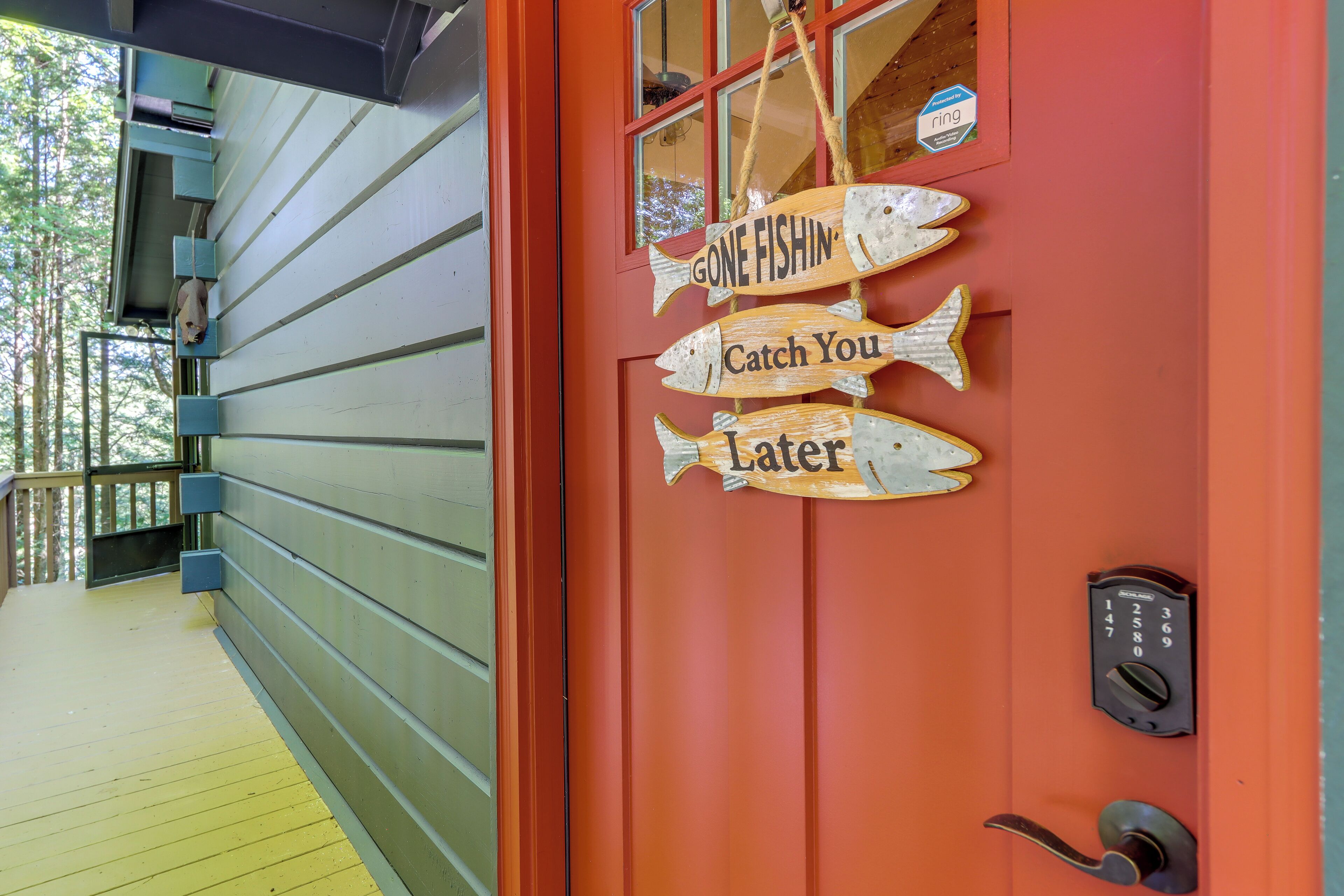 Une porte rouge avec une enseigne représentant un poisson et l’inscription « On est partis à la pêche, à plus tard », ainsi qu’un système de verrouillage à clavier.