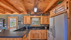 A wooden cabin kitchen with a large island, wooden cabinets, and a refrigerator.