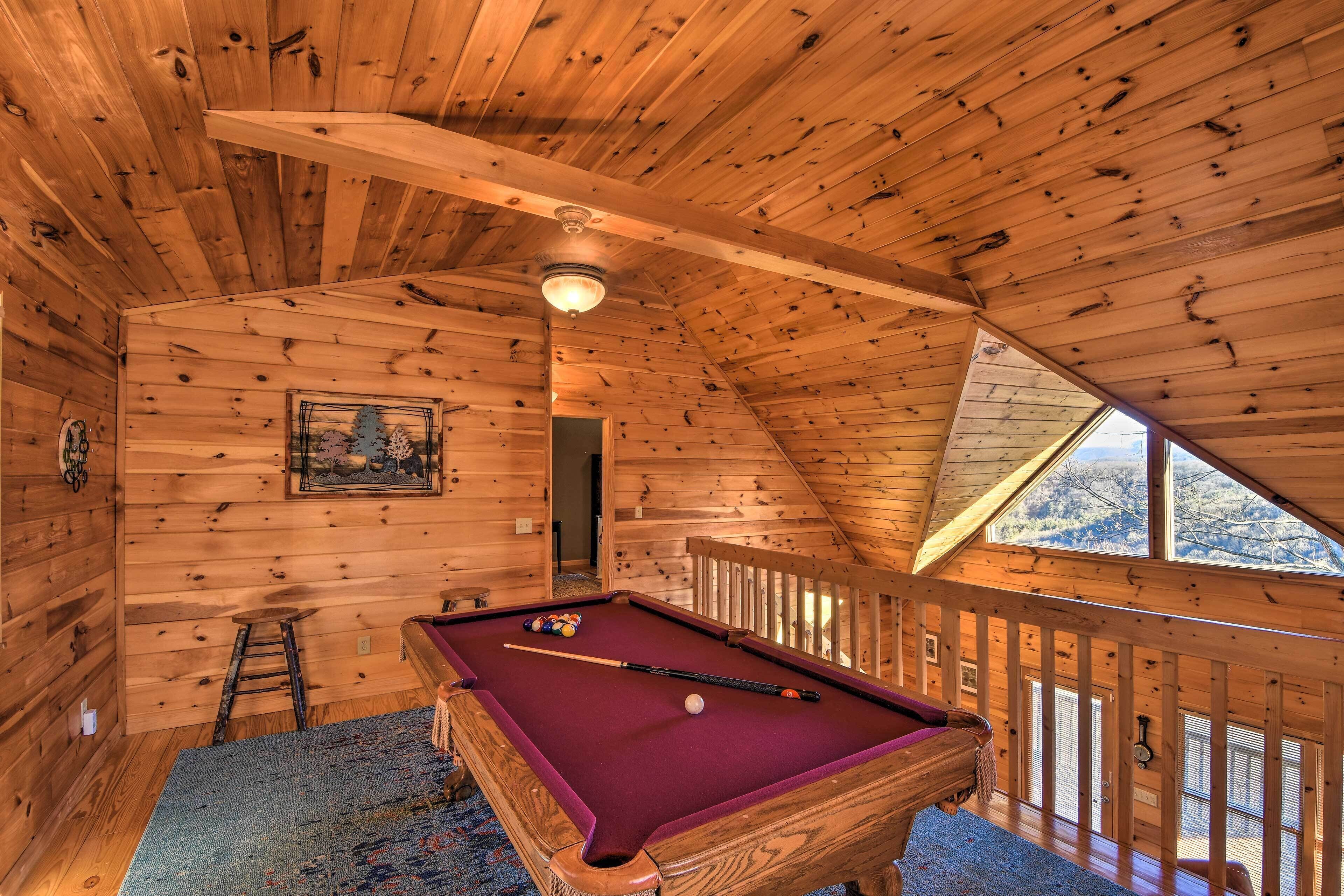 A wooden interior with a pool table, a ladder, and a railing.