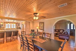 A spacious dining area with a long table, chairs, and a ceiling fan.