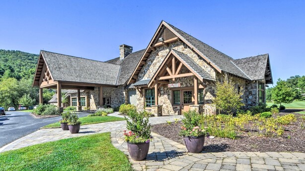 A stone building with a pitched roof, a covered porch, and a landscaped driveway with potted plants. - Sky Valley Retreat w/ Resort Amenities & Views! (Dillard)