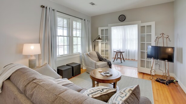 A modern living room with a sofa, coffee table, and a TV on a stand. - Charming Cottage w/ Mississippi River Views! (Natchez)