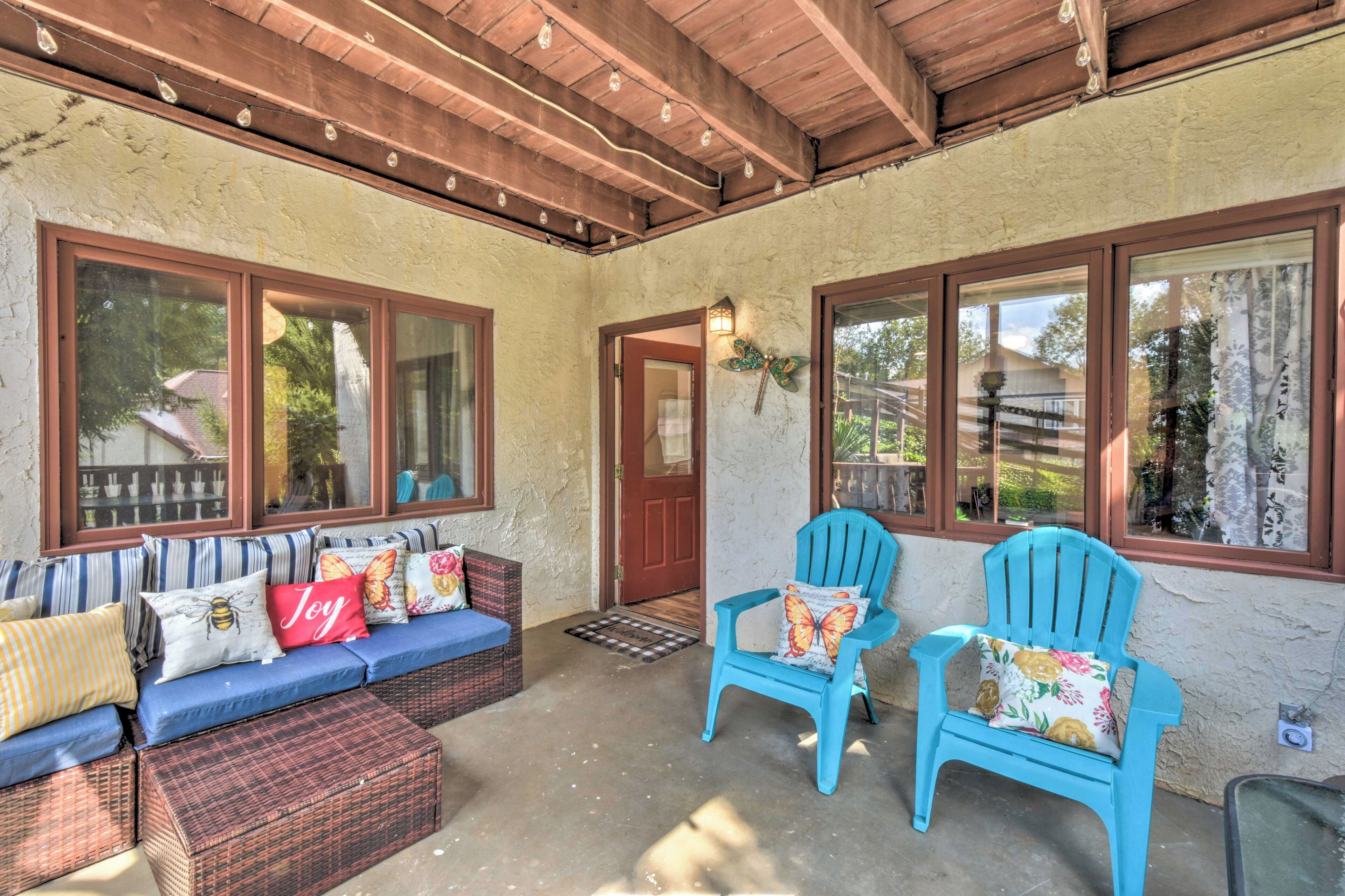 A covered porch with a blue sofa, two blue chairs, and a wooden ceiling.