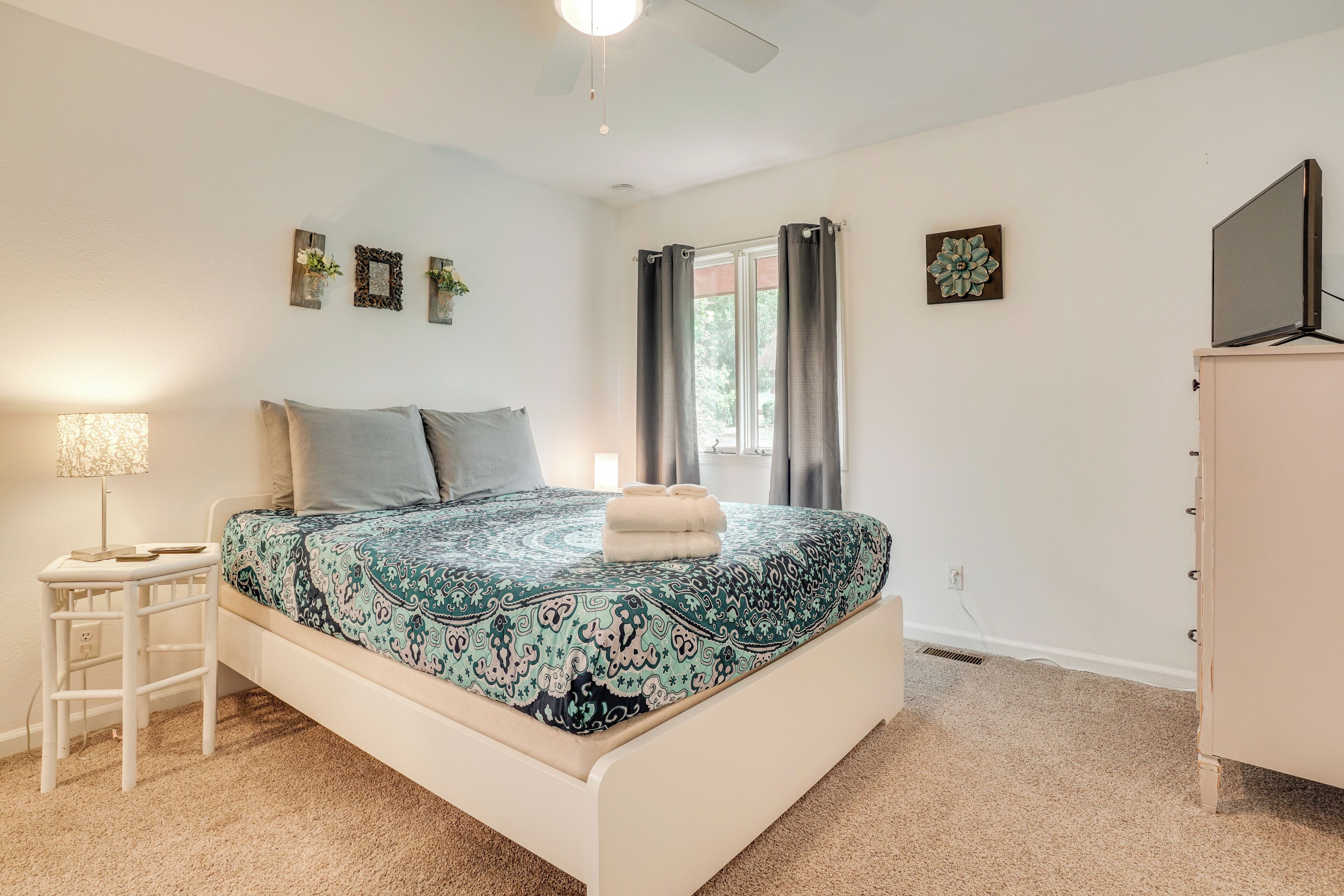A bedroom with a bed, a nightstand, a lamp, a dresser, and a TV.
