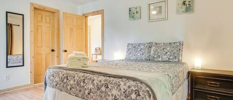 Ein Schlafzimmer mit einem Bett, Holztüren, einem Nachttisch und Wandbildern.