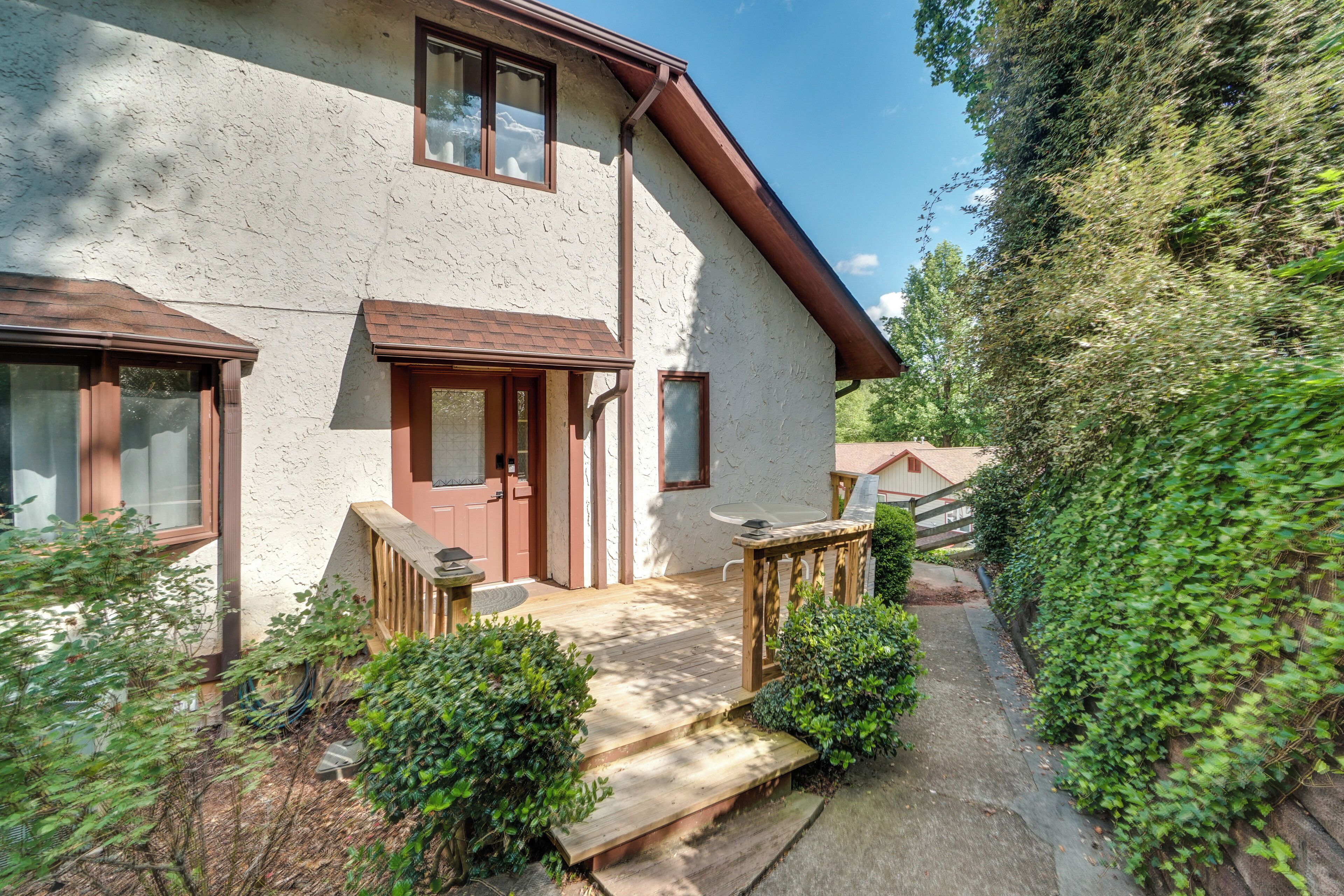 A two-story house with a wooden deck, a front door, and a small porch.
