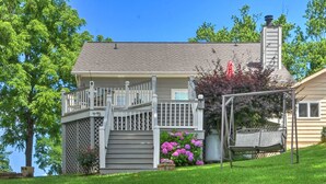 A two-story house with a front porch, a swing set, and a chimney.