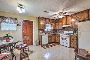 A kitchen with wooden cabinets, a white refrigerator, a stove, and a ceiling fan. - Family Home Near Panola Mountain State Park! (Lithonia)