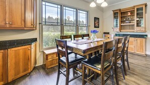 A kitchen with wooden cabinets, a dining table with chairs, and a view through large windows. - Spacious Elko Home - 6 Mi to Georgia Fairgrounds! (Elko)