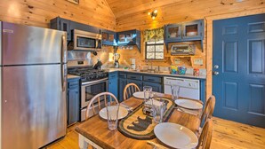Une cuisine aménagée dans une cabane en bois, équipée d’un réfrigérateur, d’une cuisinière, d’un four à micro-ondes et de placards.