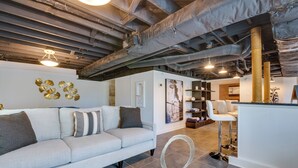 A modern living room with a light-colored sofa, a round coffee table, and a bar area with stools. - Luxury Retreat in Smyrna: Pool, Pickleball & More! (Smyrna)