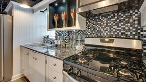 A modern kitchen with white cabinets, a black stove, and a checkered backsplash. - Luxury Retreat in Smyrna: Pool, Pickleball & More! (Smyrna)