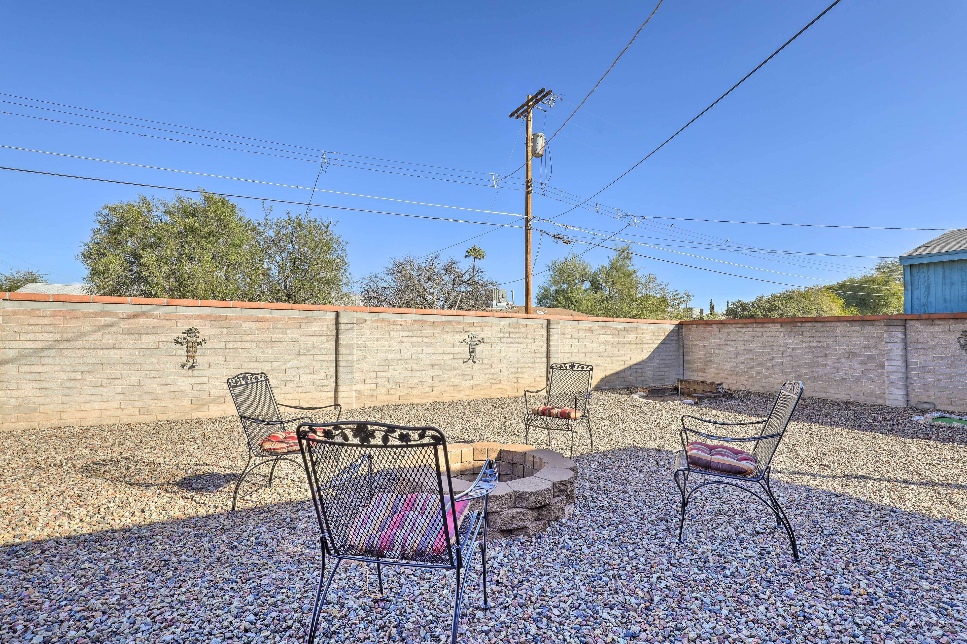 Une terrasse extérieure avec trois chaises en métal et un foyer.