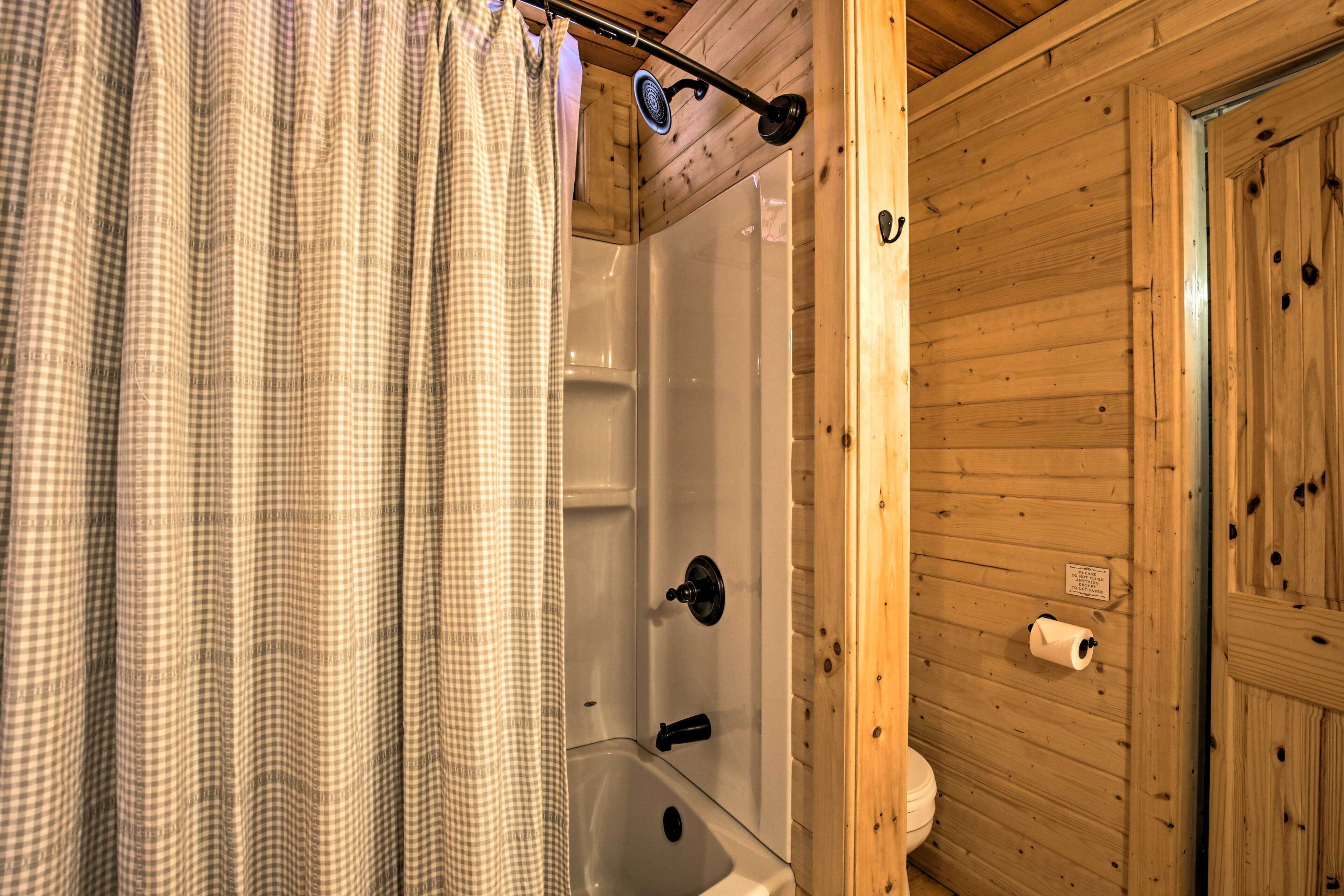 A wooden cabin bathroom with a shower, a toilet, and a sink.