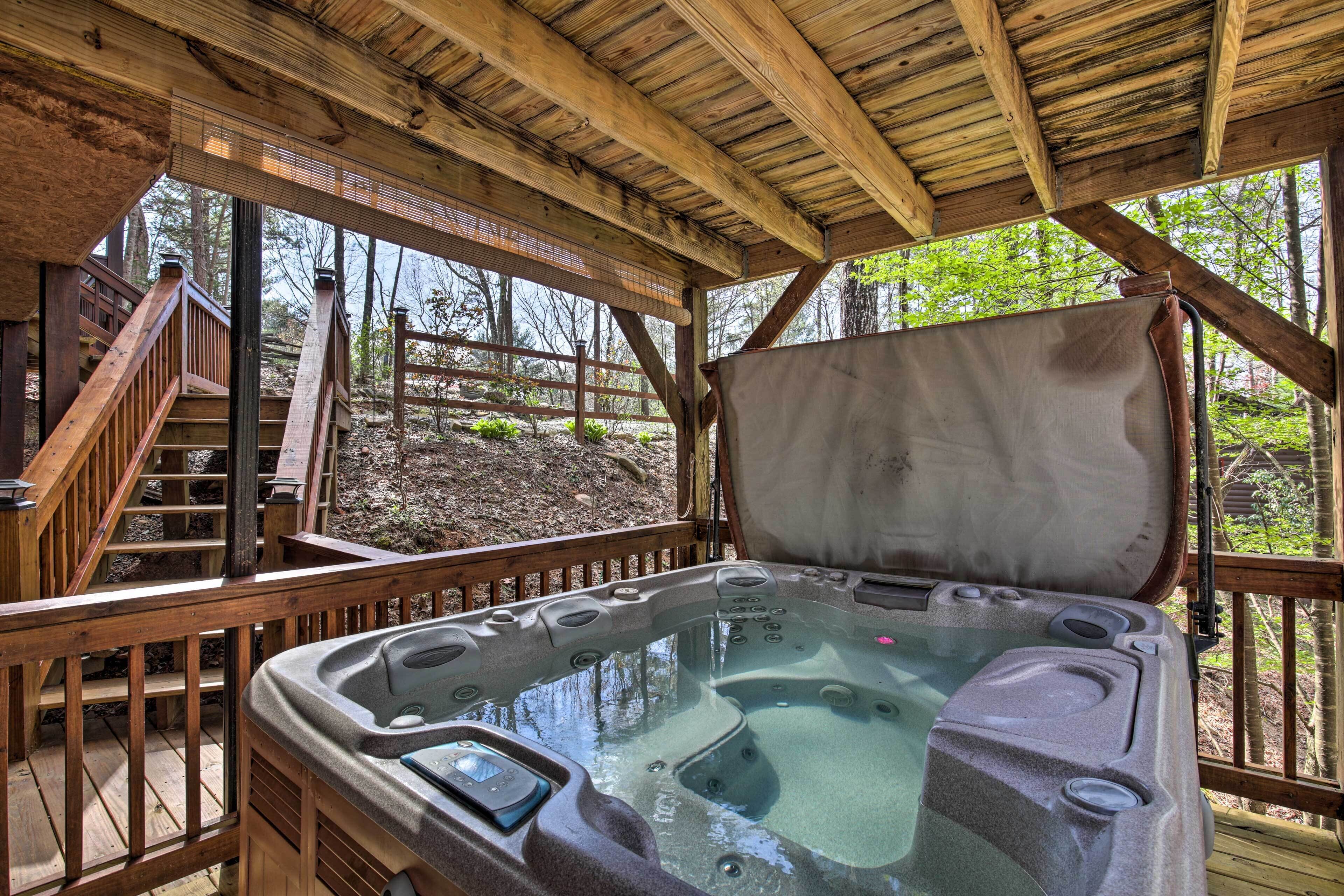 A hot tub with a wooden deck and a view of the forest.