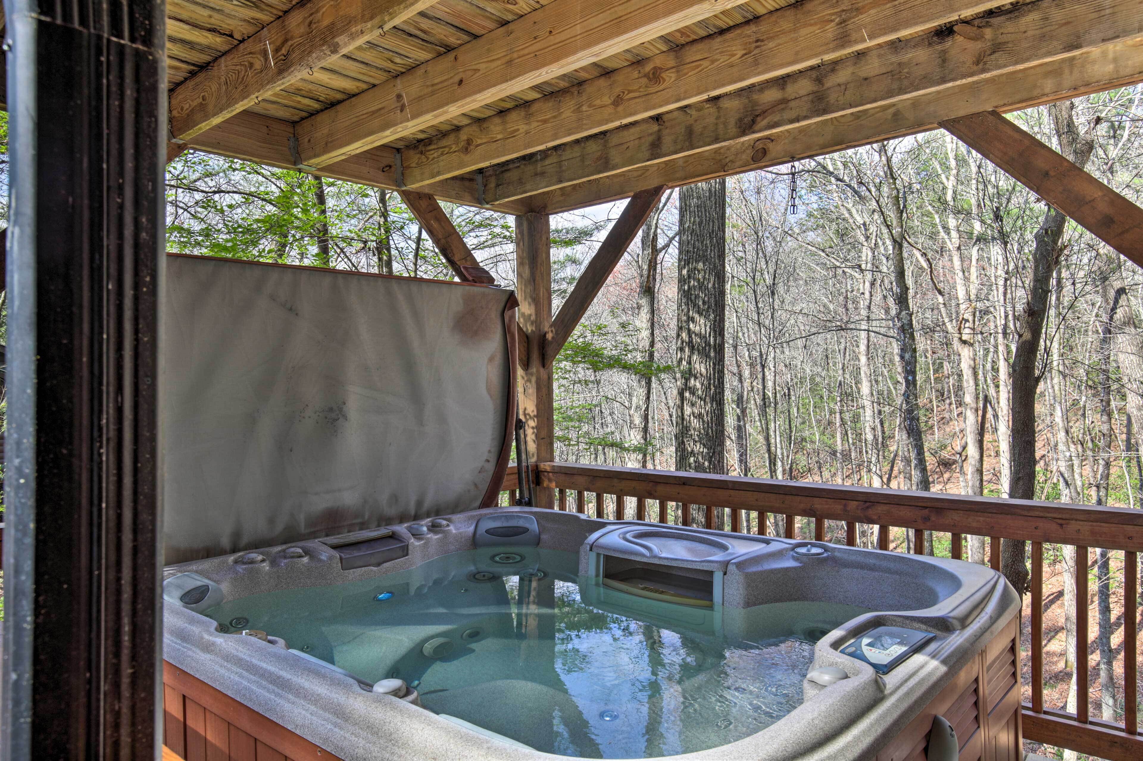 A hot tub in a wooden deck area with a view of a forest.